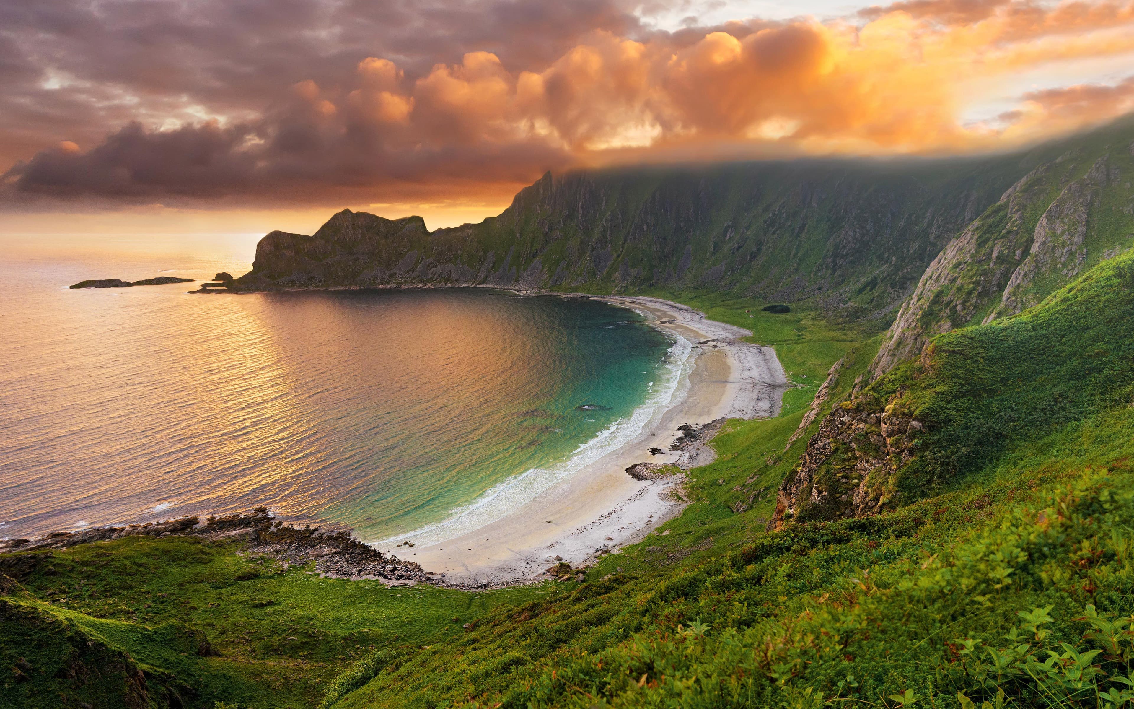 Plage entourée de montagnes sous un ciel doré